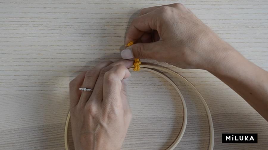 Paso dos para hacer el primer nudo del tutorial de plumas de macramé en aro de madera