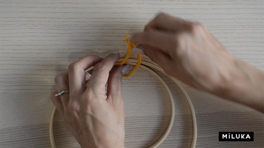 Paso uno para hacer el primer nudo del tutorial de plumas de macramé en aro de madera